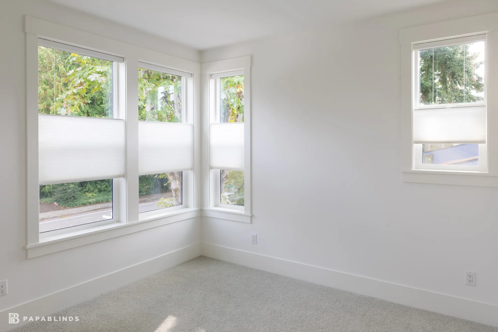 Empty room with corner windows and a side window, all fitted with white top-down bottom-up cellular shades