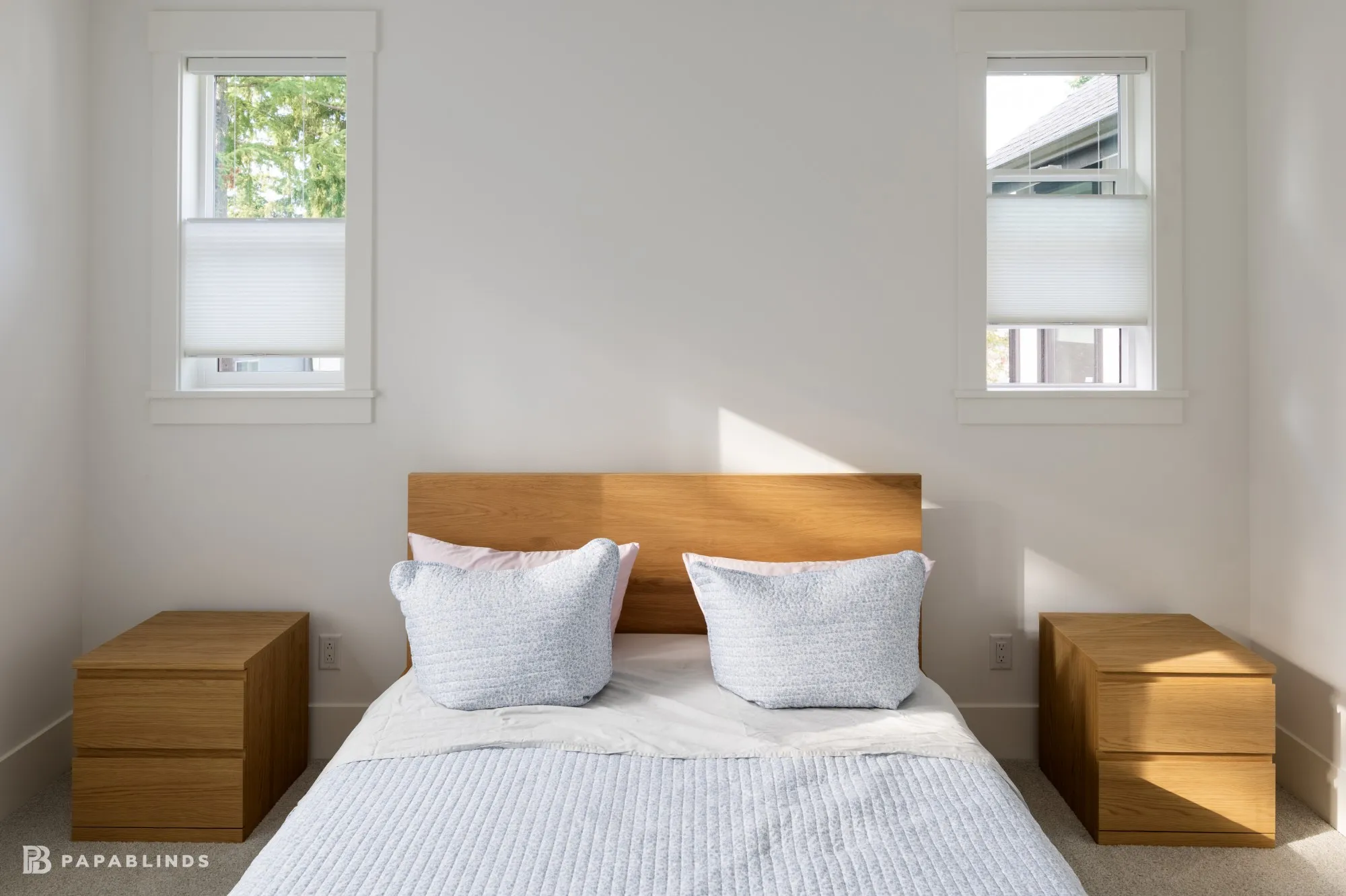 Two narrow bedroom windows above the nightstands with top-down bottom-up cellular shades lowered from the top